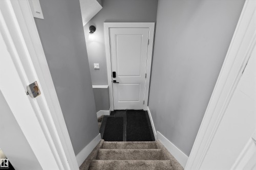 Staircase featuring neutral carpeted treads, white trim, and light gray walls - 6084 179 Avenue, Edmonton, AB 