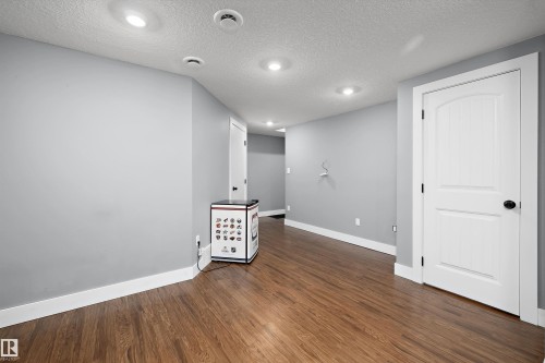 Spacious room with wood-finish flooring, light grey walls, and recessed lighting - 6084 179 Avenue, Edmonton, AB 