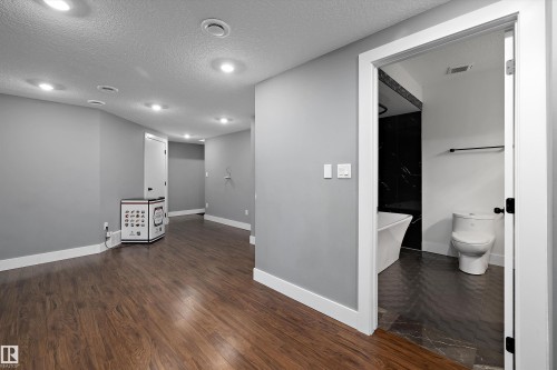 Spacious interior featuring wood-finish flooring, recessed lighting, and a neutral grey wall palette - 6084 179 Avenue, Edmonton, AB 