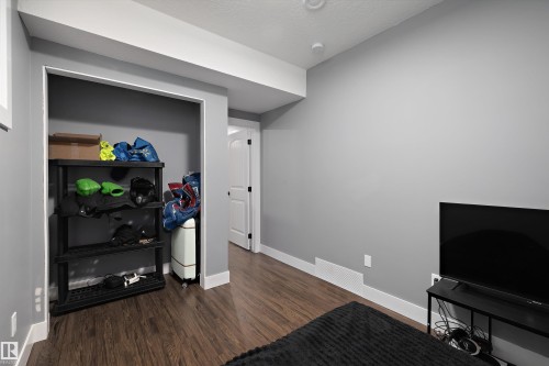 Interior room featuring wood-finish flooring, light grey painted walls, white baseboards, and white ceiling trim - 6084 179 Avenue, Edmonton, AB 