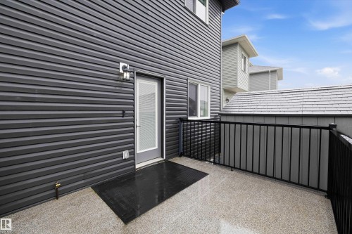 Outdoor patio featuring a textured concrete surface and black metal railings - 6084 179 Avenue, Edmonton, AB 