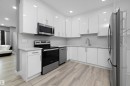 Modern kitchen featuring white cabinetry, stainless steel appliances, light-toned countertops, and a subway tile backsplash - 6084 179 Avenue, Edmonton, AB 