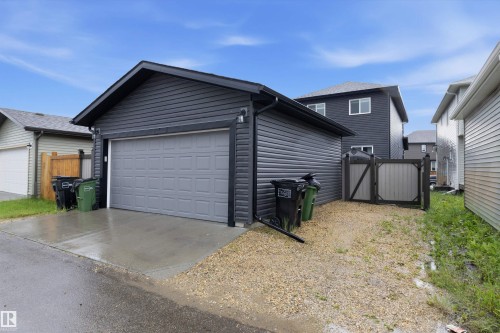 Detached garage with dark gray siding, a light gray overhead door, and concrete driveway apron - 6084 179 Avenue, Edmonton, AB 