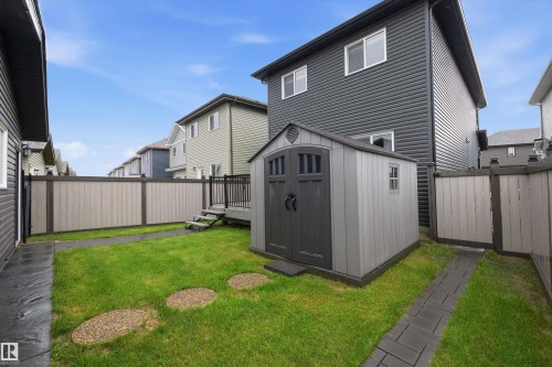 Backyard featuring a utility shed with double doors, an elevated deck with black railing, and a privacy fence - 6084 179 Avenue, Edmonton, AB 