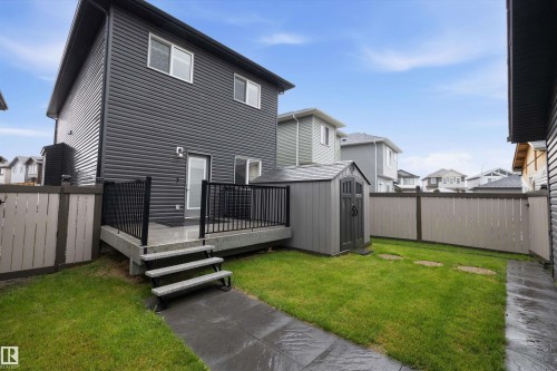 Private backyard featuring a composite deck with black metal railings, a manicured lawn, and a gray storage shed - 6084 179 Avenue, Edmonton, AB 