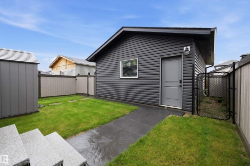 Detached garage featuring dark grey siding, a single window, and a grey entry door - 6084 179 Avenue, Edmonton, AB 