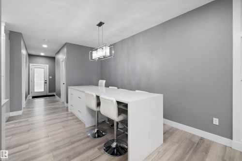 Kitchen island with seating, recessed lighting, modern chandelier, and a frosted glass door - 6084 179 Avenue, Edmonton, AB 