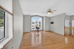 Spacious living area featuring wood-finish flooring, light gray walls, and a vaulted ceiling - 