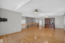 Expansive open-concept room featuring light wood-finish flooring, neutral gray walls, and a recessed ceiling fan - 