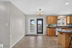 Kitchen and dining area featuring a dual-pane door, tile flooring, wood-finish cabinetry, and a bay window - 