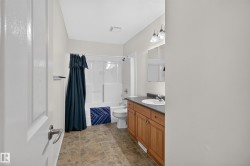 Full bathroom featuring a single vanity with wood cabinetry, a white basin, and a dark countertop - 