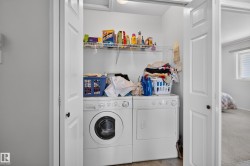 Compact laundry area featuring a front-load washer and dryer set, white wire shelving, and light wood-finish flooring - 