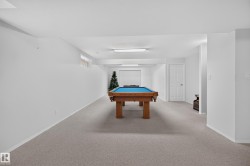 Spacious finished lower level with light gray carpeting, white walls, and recessed lighting - 