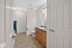 Full bathroom featuring a wood-finish vanity with an integrated sink, dark countertop, and brushed nickel hardware - 