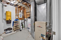 Utility space featuring a forced air furnace and hot water tank - 
