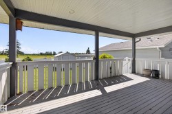 Covered outdoor deck featuring white wood-finish decking, white railings, and a white beadboard-style ceiling with recessed lighting - 