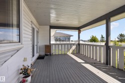 Covered outdoor deck featuring composite decking, white vertical slat railing, and a white soffit ceiling - 