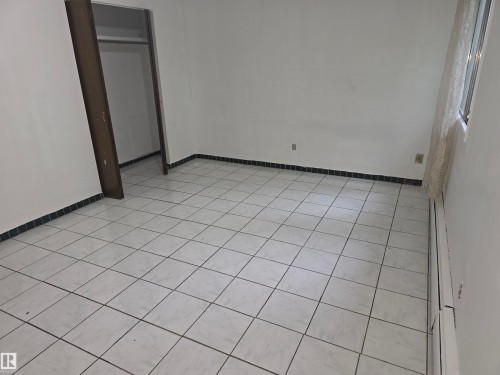 Tile flooring spanning the room, complemented by white walls and a dark tile baseboard - 307 11907 81 Street Nw, Edmonton, AB 