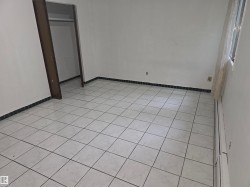 Tile flooring spanning the room, complemented by white walls and a dark tile baseboard - 