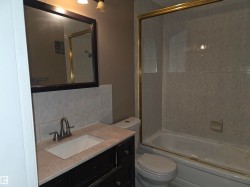 Bathroom featuring a vanity with a light-colored countertop, an undermount sink, and a dark-toned cabinet - 