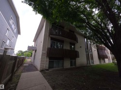 Multi-level building exterior featuring light-colored brick siding, dark-toned vertical accents, and private balconies with dark railings - 