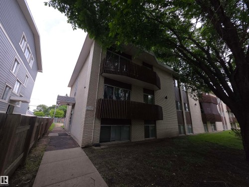 Multi-level building exterior featuring light-colored brick siding, dark-toned vertical accents, and private balconies with dark railings - #307 11907 81 St Nw Nw, Edmonton, AB 