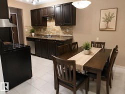 Kitchen and dining area featuring dark wood-finish cabinetry, stone-finish backsplash, stainless steel appliances, and light tile flooring - 