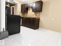 Kitchen featuring dark wood-finish cabinetry, tile backsplash, stainless steel sink, and light tile flooring - 307 11907 81 Street Nw, Edmonton, AB 