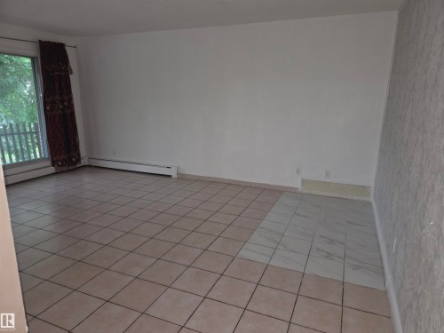 Spacious room featuring a large window, tile flooring, and clean white walls - 307 11907 81 Street Nw, Edmonton, AB 