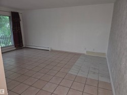 Spacious room featuring a large window, tile flooring, and clean white walls - 