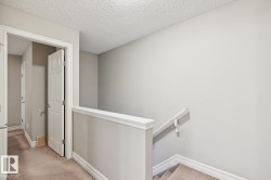 Upper landing with neutral wall paint, carpeted flooring, and white trim molding - 