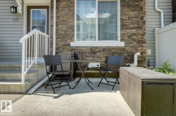 Concrete patio space featuring a stone-clad exterior wall and a white vinyl privacy fence - 