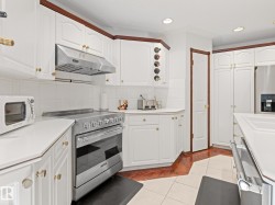 Kitchen featuring stainless steel appliances, decorative backsplash, under cabinet range hood, light tile patterned flooring, and light countertops - 