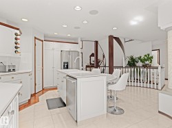 Kitchen featuring white cabinetry, light countertops, a kitchen breakfast bar, recessed lighting, and a kitchen island with sink - 