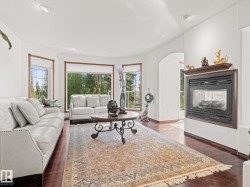 Living area featuring a multi sided fireplace, healthy amount of natural light, dark wood finished floors, and recessed lighting - 