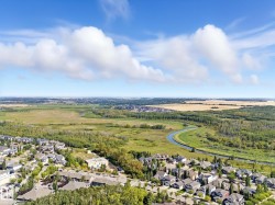 Aerial view of residential area featuring a heavily wooded area and a large body of water - 