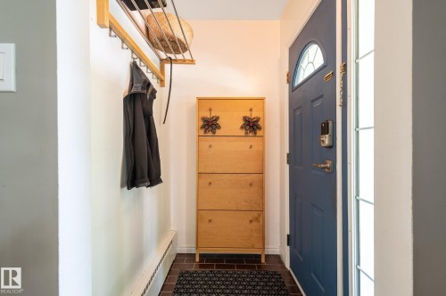 Entryway featuring a paneled door with an arched window, a tall wooden storage cabinet, and a wall-mounted coat rack - 11634 74 Avenue Nw, Edmonton, AB 
