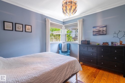 Light-filled room featuring wood-finish flooring, corner windows with white trim, and crown molding - 11634 74 Avenue Nw, Edmonton, AB 