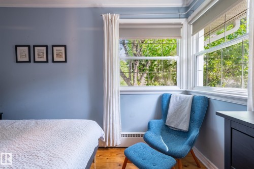 Room featuring wood-finish flooring, light blue wall paint, white crown molding, and two windows with white trim - 11634 74 Avenue Nw, Edmonton, AB 
