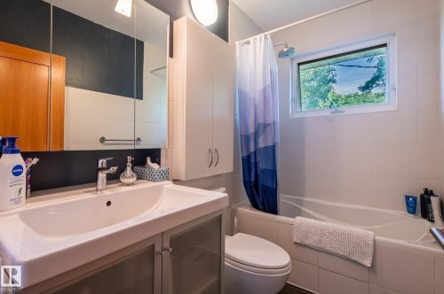 Bathroom featuring a white vanity with integrated sink, chrome faucet, and mirrored medicine cabinet - 11634 74 Avenue Nw, Edmonton, AB 