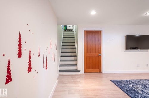 Light wood-finish flooring complements a solid wood-panel door with brushed nickel hardware - 11634 74 Avenue Nw, Edmonton, AB 
