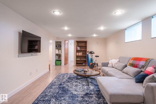 Spacious recreation room featuring recessed lighting, wood-finish flooring, and built-in shelving - 11634 74 Avenue Nw, Edmonton, AB 