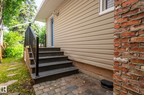 Exterior entryway featuring a multi-level deck with black railings, a paver patio, and stone stepping-stones across the lawn - 11634 74 Avenue Nw, Edmonton, AB 