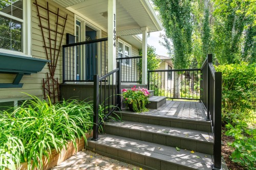 Front porch featuring composite decking and steps, black metal railings, and a siding exterior - 11634 74 Avenue Nw, Edmonton, AB 