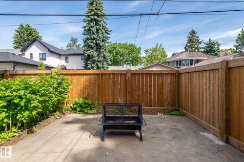 Paved patio area featuring a privacy fence, mature perimeter shrubs, and established trees - 11634 74 Avenue Nw, Edmonton, AB 