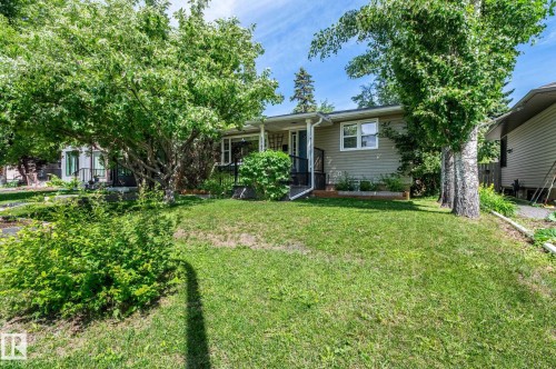 Front exterior featuring neutral siding, white trim windows, and a covered entry - 11634 74 Avenue Nw, Edmonton, AB 