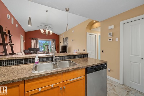 Kitchen featuring a double basin stainless steel sink, a dishwasher, and wood-finish cabinetry - 30 2565 Hanna Crescent, Edmonton, AB 