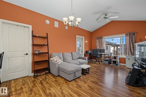 Spacious room featuring wood-finish flooring, vaulted ceilings, and a large picture window with decorative drapes - 30 2565 Hanna Crescent, Edmonton, AB 