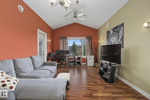 Living area featuring vaulted ceilings, wood-finish flooring, a ceiling fan, and sconce lighting - 30 2565 Hanna Crescent, Edmonton, AB 
