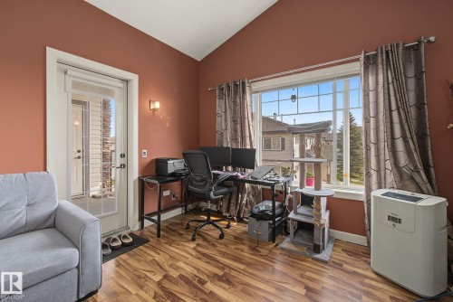 Bright room featuring a large window, a glass-paned exterior door, vaulted ceilings, and wood-finish flooring - 30 2565 Hanna Crescent, Edmonton, AB 